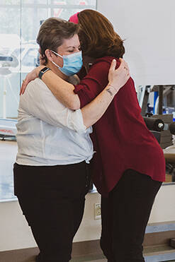 A participant and staff member hug