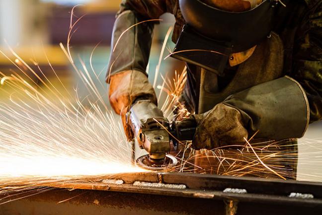 Industrial worker grinding metal with sparks flying