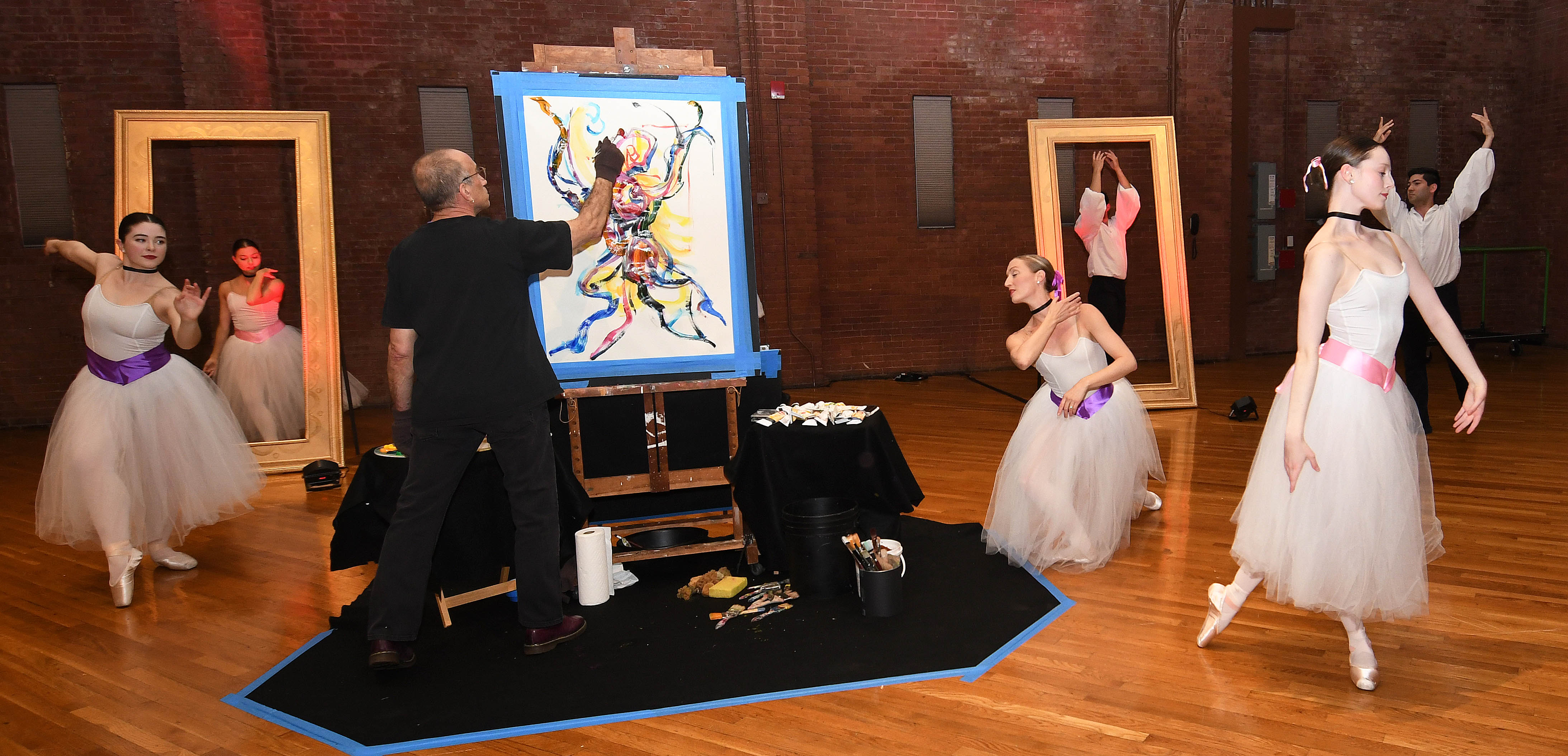 A man painting with dancers