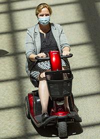 Woman, masked riding on mobility scooter at Dartmouth-Hitchcock Medical Center