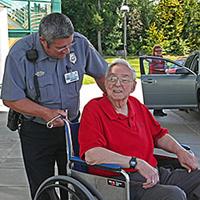 Security employee with patient in wheelchair at Main Entrance