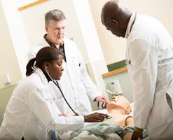 3 students in Sim Center learning room with mannequin