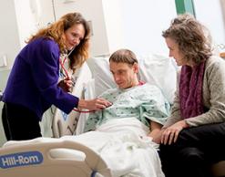 Patient in hospital bed with two provider - simulation patient