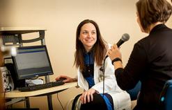 A speech language therapist works with a patient using a microphone.