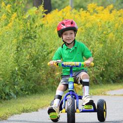Child wearing a helmet while riding a tricycle