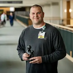 A male health care provider holding a Daisy Award Statuette