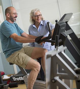 Patient on stationary bike while therapist observes