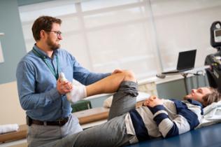 Physical therapist helps patient with knee exercises