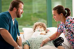 Two Training Center student working with Mannikin in hosptial bed