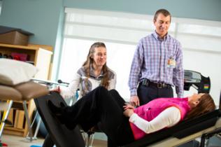 Therapists work with a patient on an incline bench.