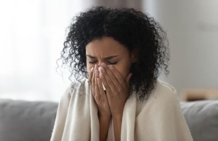african-american woman sneezing into a tissue