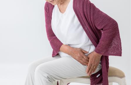 Women sitting in chair holding her hip.