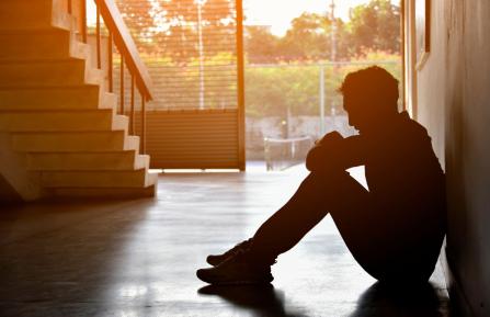 Silhouetted image of a man sitting with his knees pulled up
