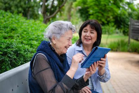 Two women on a park bench looking at a tablet