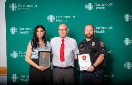 Thara S. Ali, MD, and Officer Eric Hunter hold awards and stand on either side of Terry Dion.