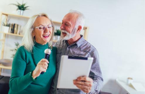 Image shows an elderly woman and man singing together.