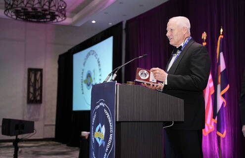 Jay Buckey Jr., MD, stands at a podium to accept his award.