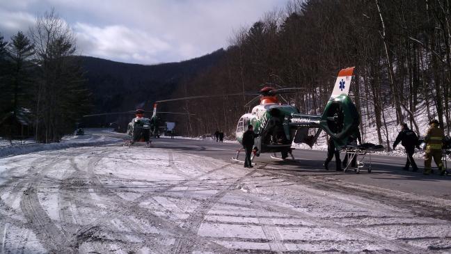 Two DHART helicopters are parked in a landing zone.