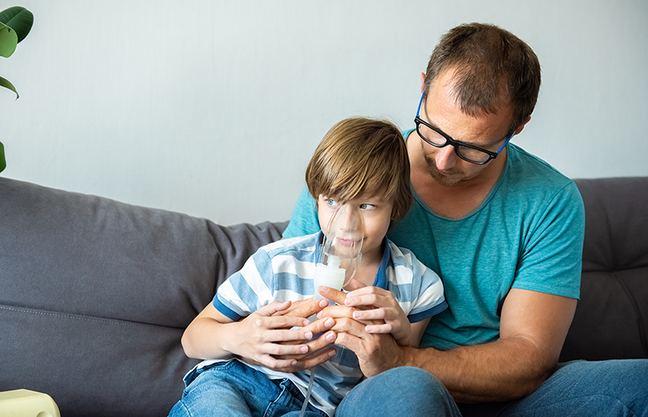 Child using nebulizer in father's lap