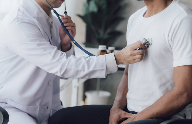 Doctor holding a stethoscope to a patient's chest