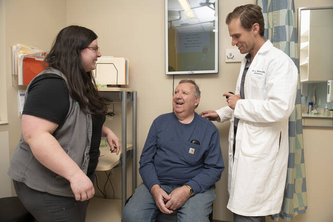 Taylor Leoutsakos and Brian Simmons, MD in clinic with a patient.