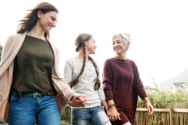 Three women holding hands and walking outside